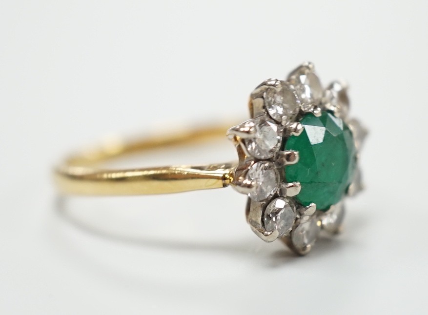 An 18ct, emerald and diamond set circular cluster ring, size K, gross weight 3 grams.
